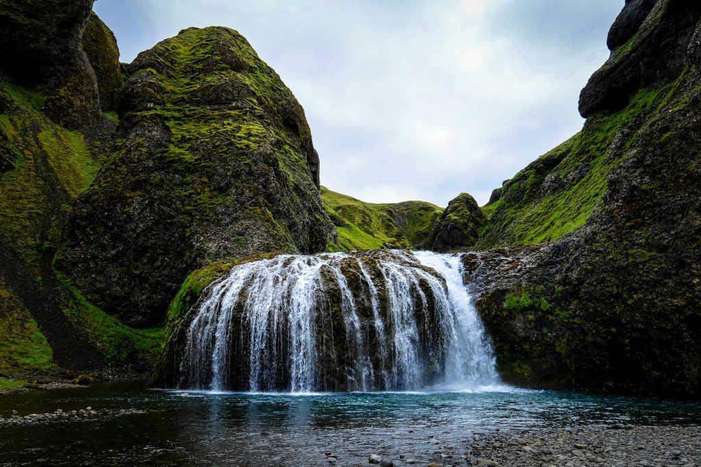 A beautiful waterfall cascading over moss-covered rocks in a mountain landscape, showcasing nature's serene beauty.