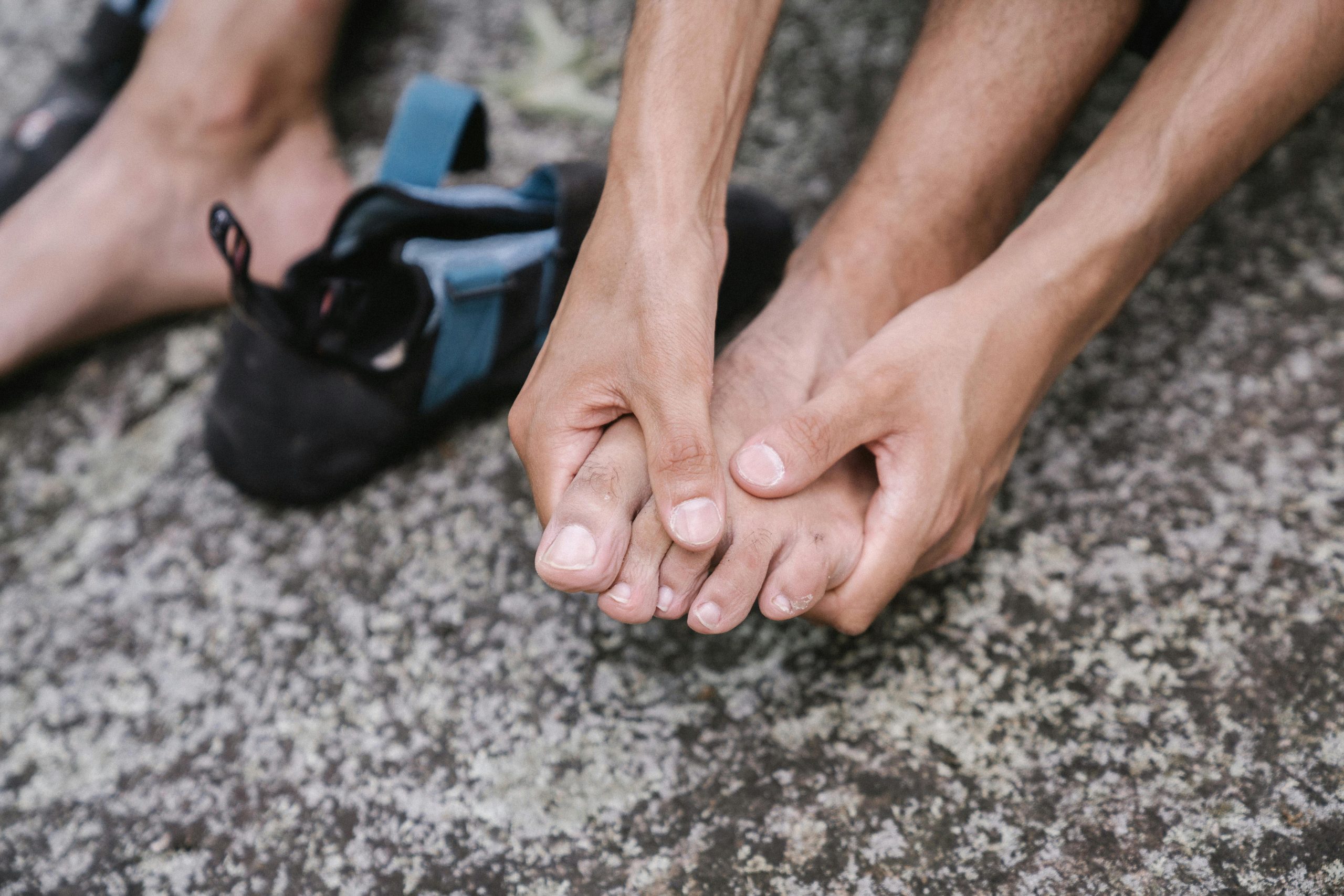 A person outdoors massaging their bare feet, conveying relaxation and care.